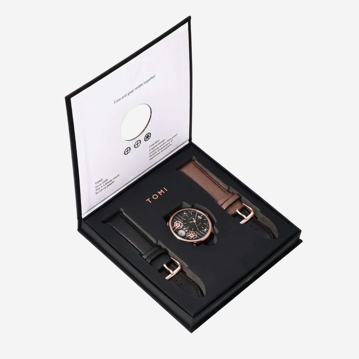 A Tumi watch gift set displayed in an open black presentation box on a light gray background. The set includes a rose gold chronograph watch with a black dial and a brown leather strap, alongside a second black leather strap with a rose gold buckle.