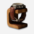 Watch with brown leather strap on a wooden stand against a white background