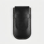A black leather card holder or wallet with light beige contrast stitching, shown flat against a light gray background.