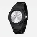 A black metal watch with a silver sunburst dial, shown resting on a textured stone surface against a f3f3f3 background.