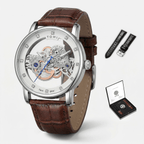 Watch with brown leather strap and visible mechanism, accompanied by additional straps and a display case on a white background.