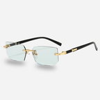 Sunglasses with gold frames and clear lenses on a light gray background