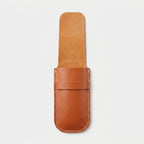 A tan leather knife sheath or pouch with a stitched edge and a strap closure, shown against a plain light gray background.