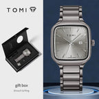Silver watch with gift box and brooch & ring on a blue background, featuring the TOMI brand.