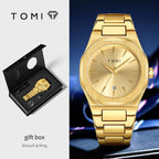 TOMI gold-tone brooch and ring set shown with the watch on the right and the open gift box on the left. The watch has an octagonal bezel, gold dial, and matching gold bracelet.