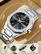 A silver stainless steel wristwatch with a brushed silver bezel, black dial, and matching metal link bracelet, displayed on a beige surface. The watch face shows the brand name 'TOMI'.