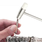 Hand using a small tool to adjust a watch on a white background