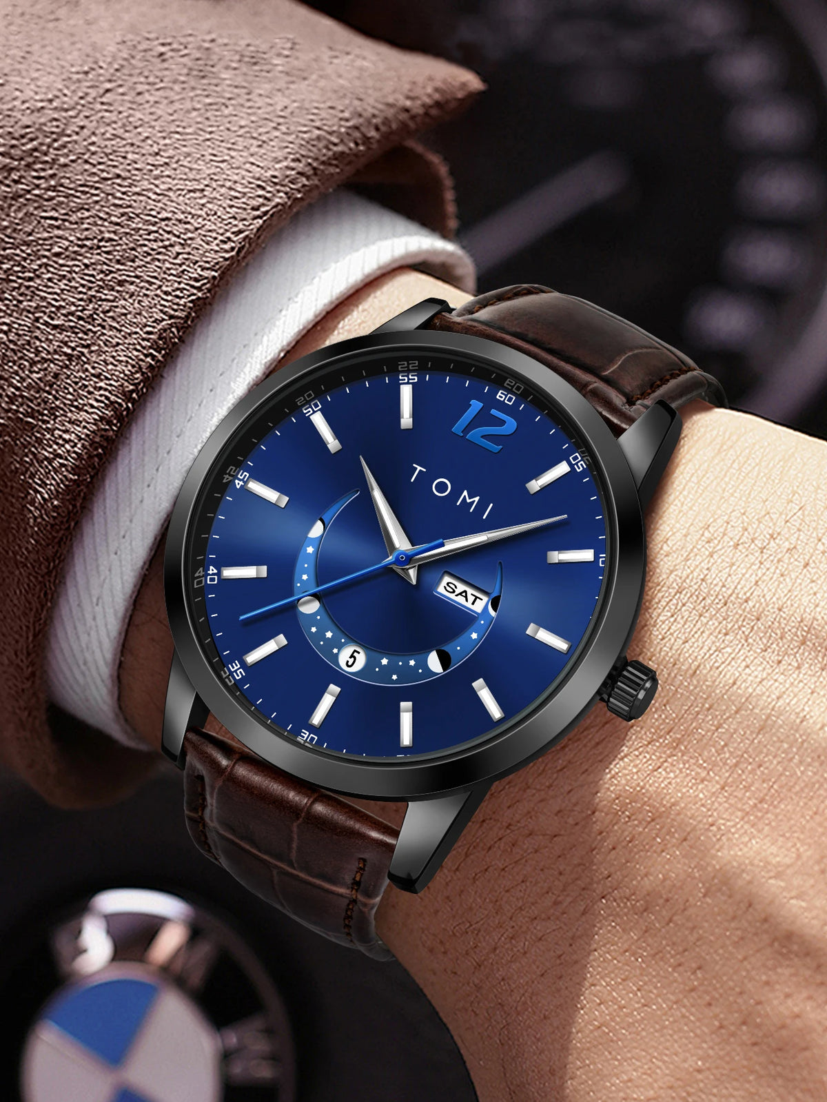Wristwatch with blue dial and brown leather strap on a wrist, brand 'TOMI' visible.