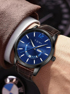 Wristwatch with blue dial and brown leather strap on a wrist, brand 'TOMI' visible.