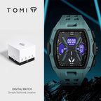 Tomi digital watch with a rugged dark green-gray case and black bezel, featuring a blue and black digital display. The left half shows the white and black TOMI product box on a light gray background, with the brand name TOMI at the top and 'DIGITAL WATCH' at the bottom.