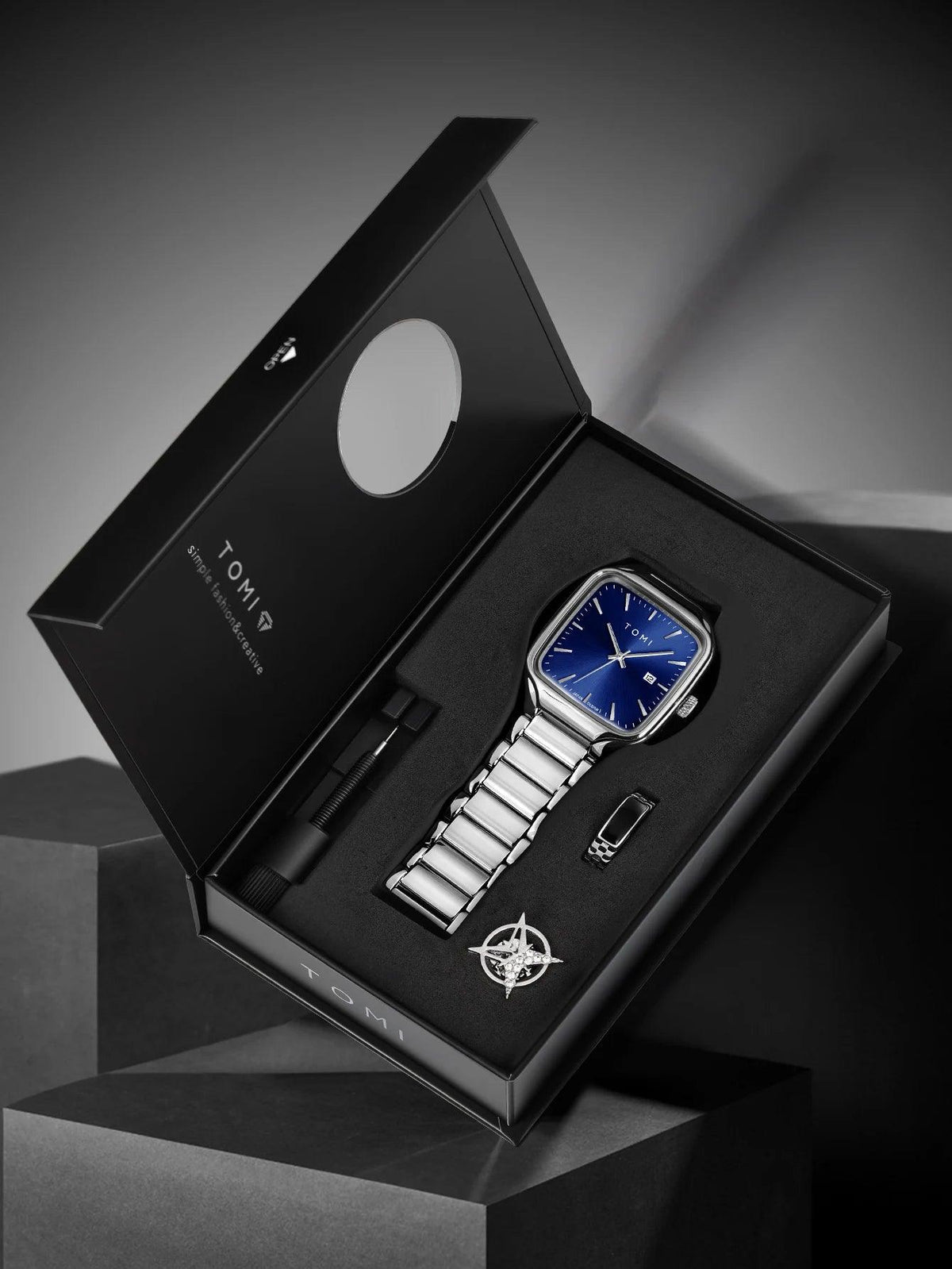 Luxury watch set with silver watch, pen, and cufflinks in a TOM FORD box on a dark background.