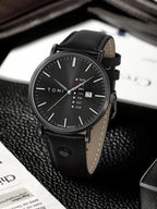 Black wristwatch with leather strap on a textured surface