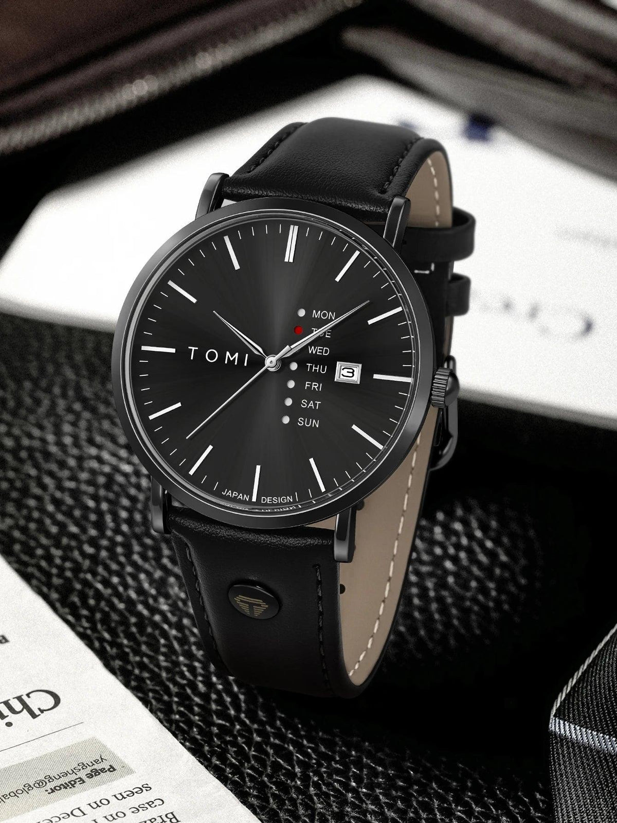 Black wristwatch with leather strap on a textured surface