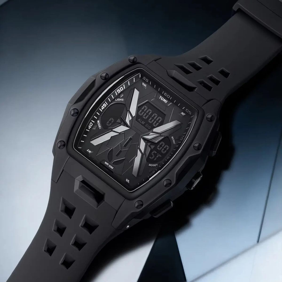 A rugged black digital-analog wristwatch with a matte black silicone strap, shown at an angle on a dark blue and gray background.