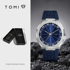 TOMI men's watch with a brushed silver-tone octagonal case, deep blue dial, and blue silicone strap, shown alongside its black presentation box on a split white and dark gray background.