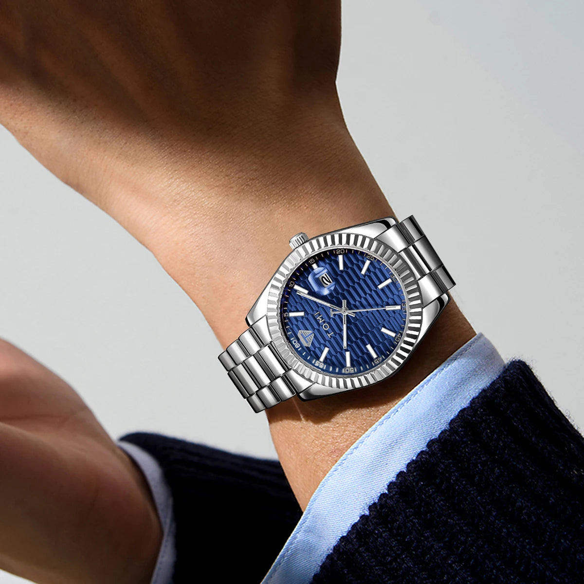 Silver watch with a blue face on a wrist against a neutral background