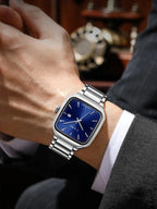 Silver watch with a blue face on a person's wrist, blurred background