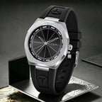A TOMI men's watch with a brushed silver-tone octagonal bezel, black dial, and black rubber strap, displayed on a metallic stand against a dark gray background.