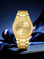 A gold-tone stainless steel wrist watch with a matching metal link bracelet, featuring a brushed dial, slim stick indices, and a date window at the 3 o'clock position. The brand name 'TOMI' is printed on the dial.