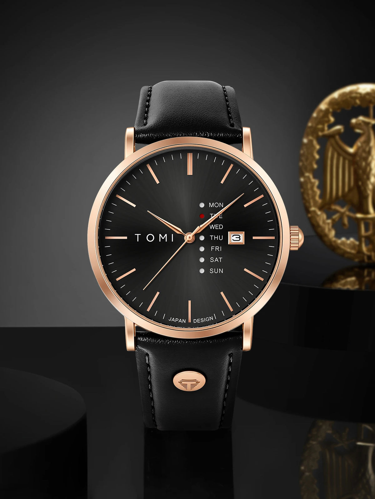 Black watch with rose gold case and black leather strap on a dark background