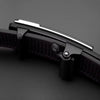 Close-up of a black knife blade with a metallic handle on a dark background
