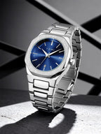 A Tumi stainless steel wristwatch with a blue sunburst dial, standing on a textured gray surface with dramatic shadows against a dark gray background.