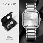 Silver watch with gift box and brooch & ring on a dark background, featuring the TOMI brand.