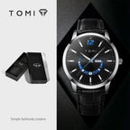 Black wristwatch with leather strap and detailed face, displayed with TOMI packaging on a dark background.