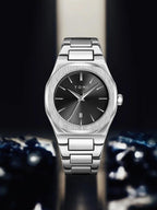 A TOMI men's watch with a brushed silver stainless steel case and bracelet, featuring a dark gray dial with silver hands and indices.