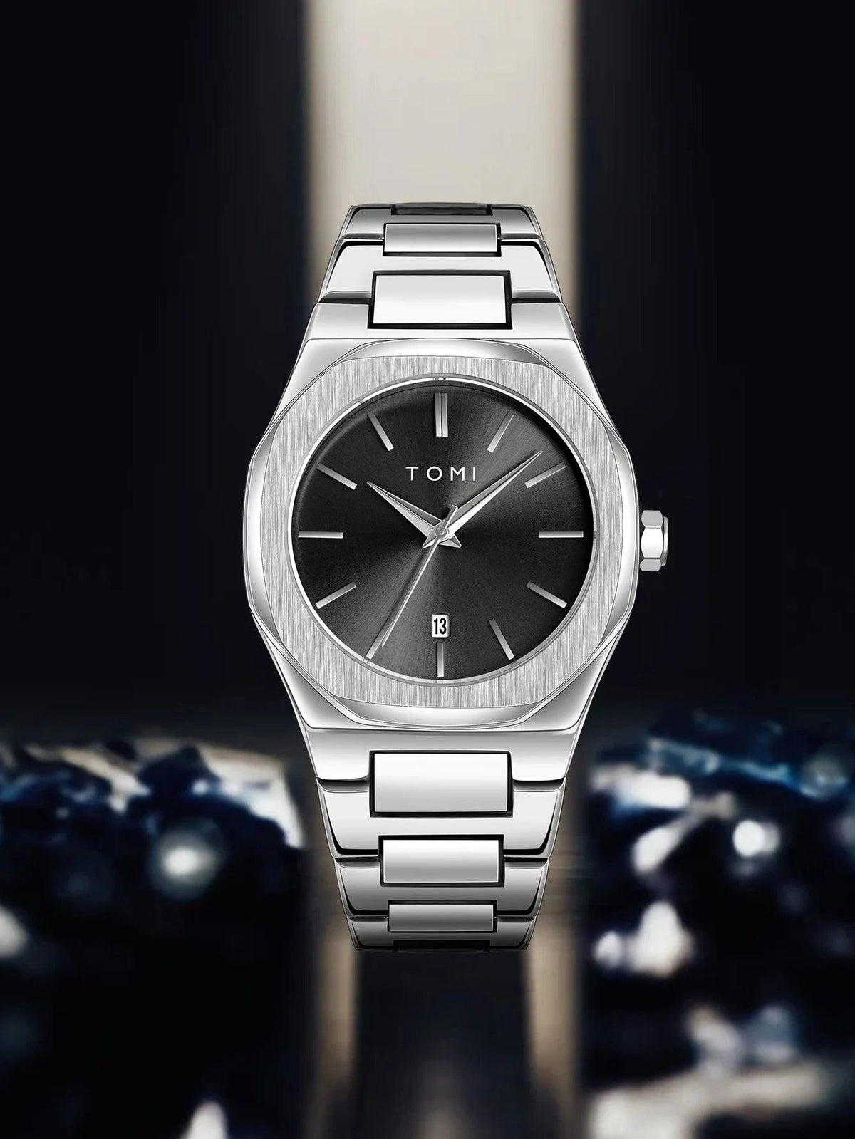 A TOMI men's watch with a brushed silver stainless steel case and bracelet, featuring a dark gray dial with silver hands and indices.