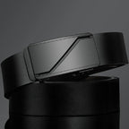 Black leather belt with a metallic buckle on a dark background