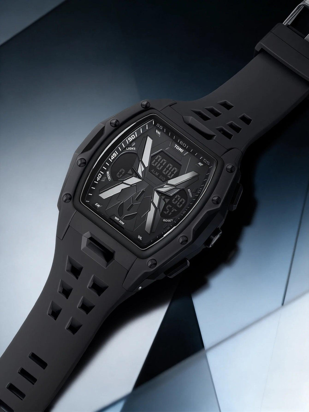 A rugged black digital-analog watch with a matte black strap and a dark face, photographed diagonally on a glossy blue and gray surface.
