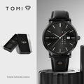 Black watch with leather strap and 'TOMI' branding on a gray background