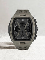 A rugged tactical watch with an olive green and black case and strap, featuring a digital display on a light gray textured background.