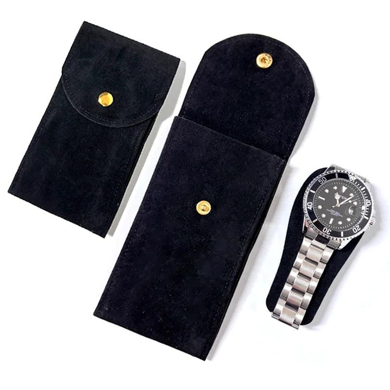 Black velvet watch pouches with gold buttons and a silver watch on a white background