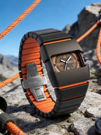 Watch with orange and black strap on a rocky surface with mountains in the background