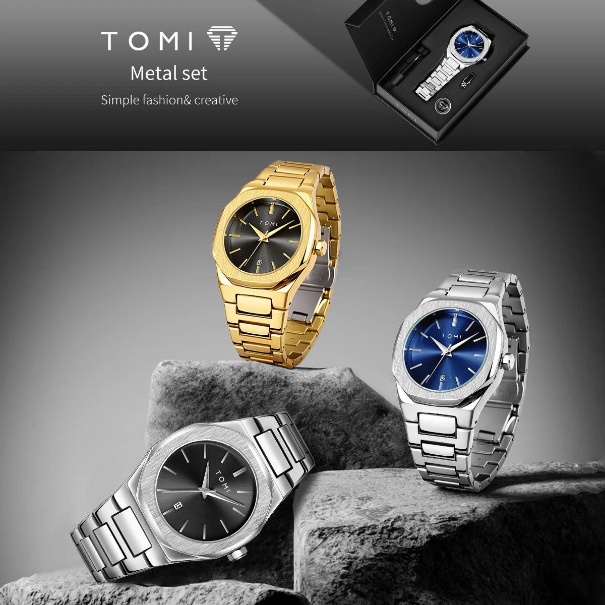Three TOMI metal link watches are displayed on dark stone blocks against a gray gradient background, with a black presentation box shown in the top right. The watches feature gold, silver, and blue dials.