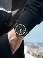 Person wearing a black watch with a blurred cityscape background