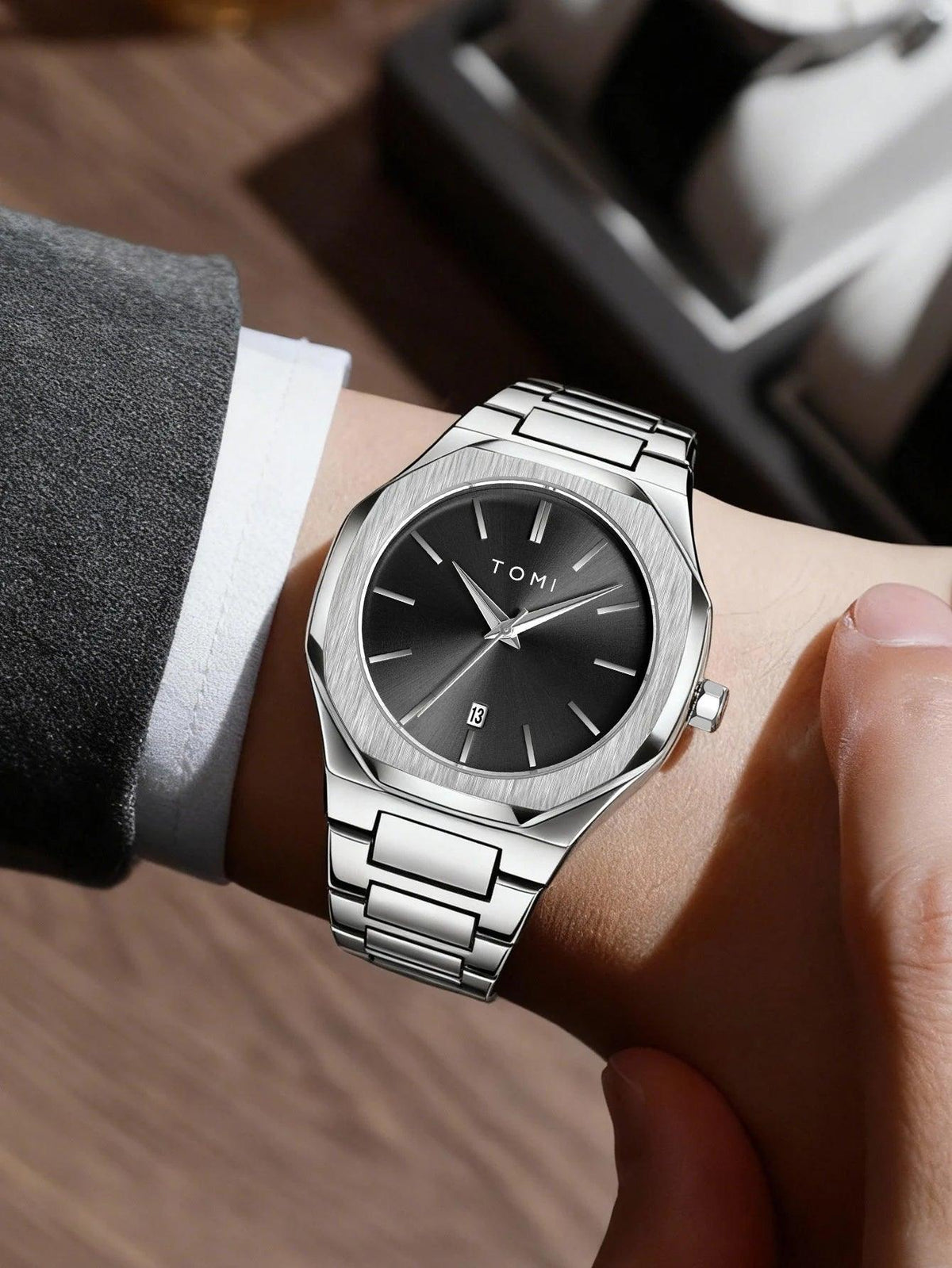 Silver watch with black dial on a wrist, brand 'TONI' visible