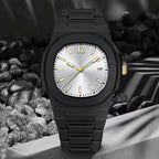 A black metal wristwatch with an octagonal bezel, a silver-toned dial, and gold-tone hands and hour markers, displayed on a gray pedestal with dark pebbles in the background.