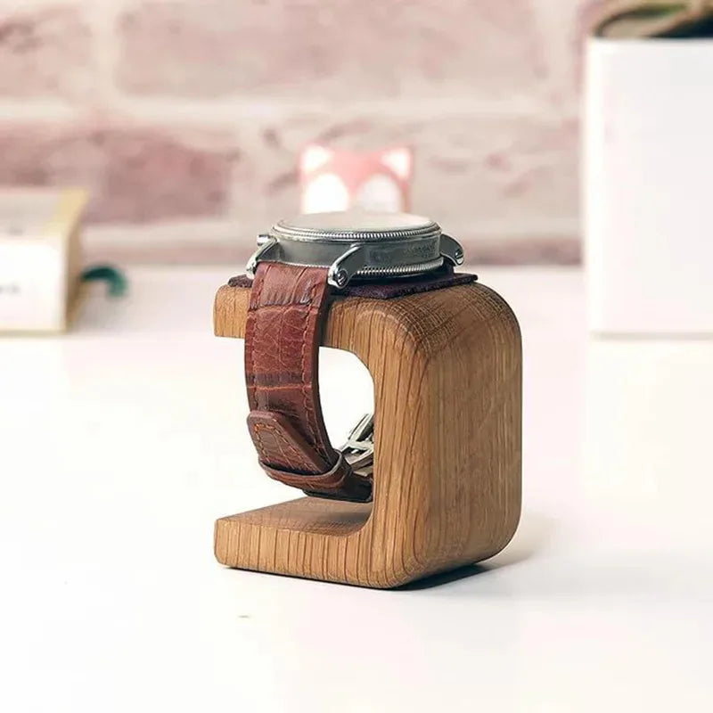 Wooden watch stand with a leather strap holding a watch on a blurred background