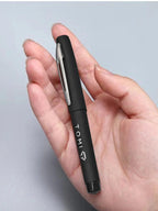 Black pen with silver clip held in a hand against a light gray background