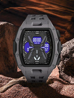 A rugged dark gray digital watch with a textured black case and blue display, set against a desert rock background.