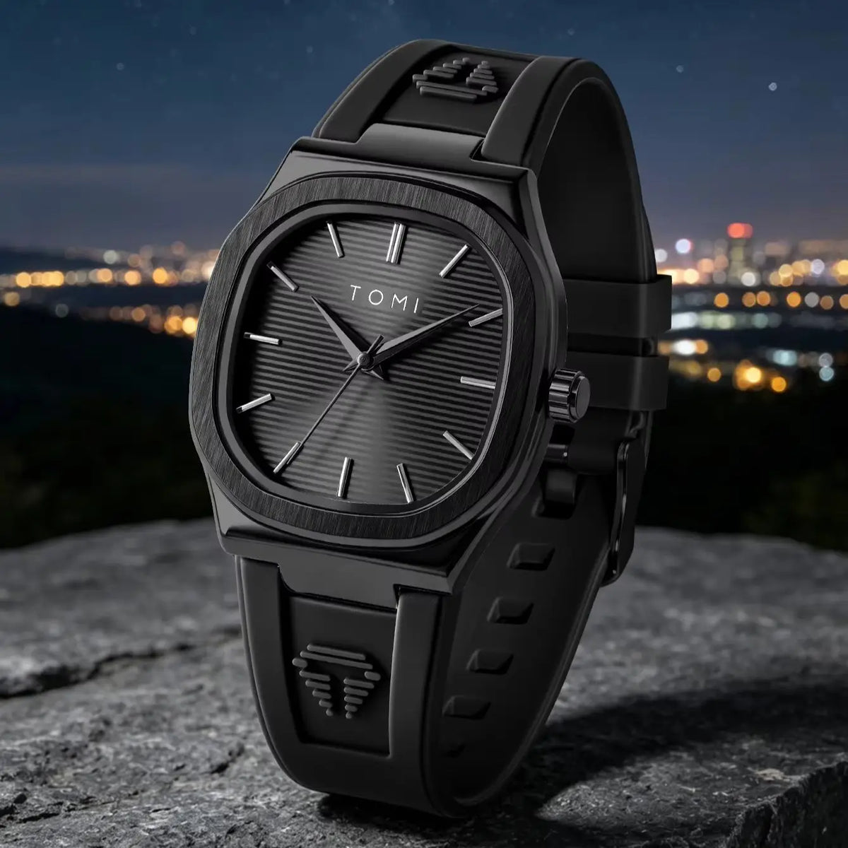 A black Tumi wristwatch with a matte rubber strap and a textured black dial, resting on a dark stone surface with a blurred night cityscape in the background.