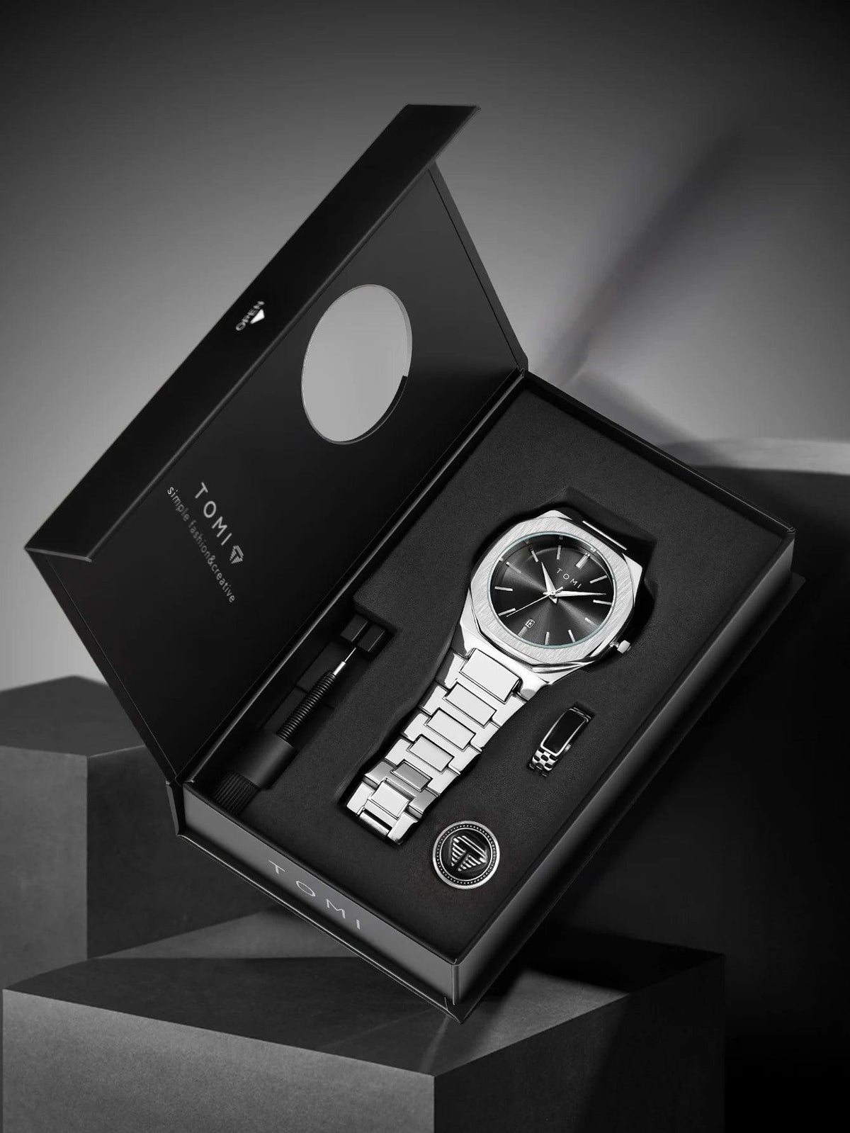 Silver watch with black face in a black box on a gray background