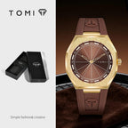 TOMI men's watch featuring a brushed gold-tone case, a brown dial, and a brown silicone strap with an embossed logo. The image is split into two sections: the left shows the black TOMI presentation box, and the right shows the watch on a dark brown textured surface.