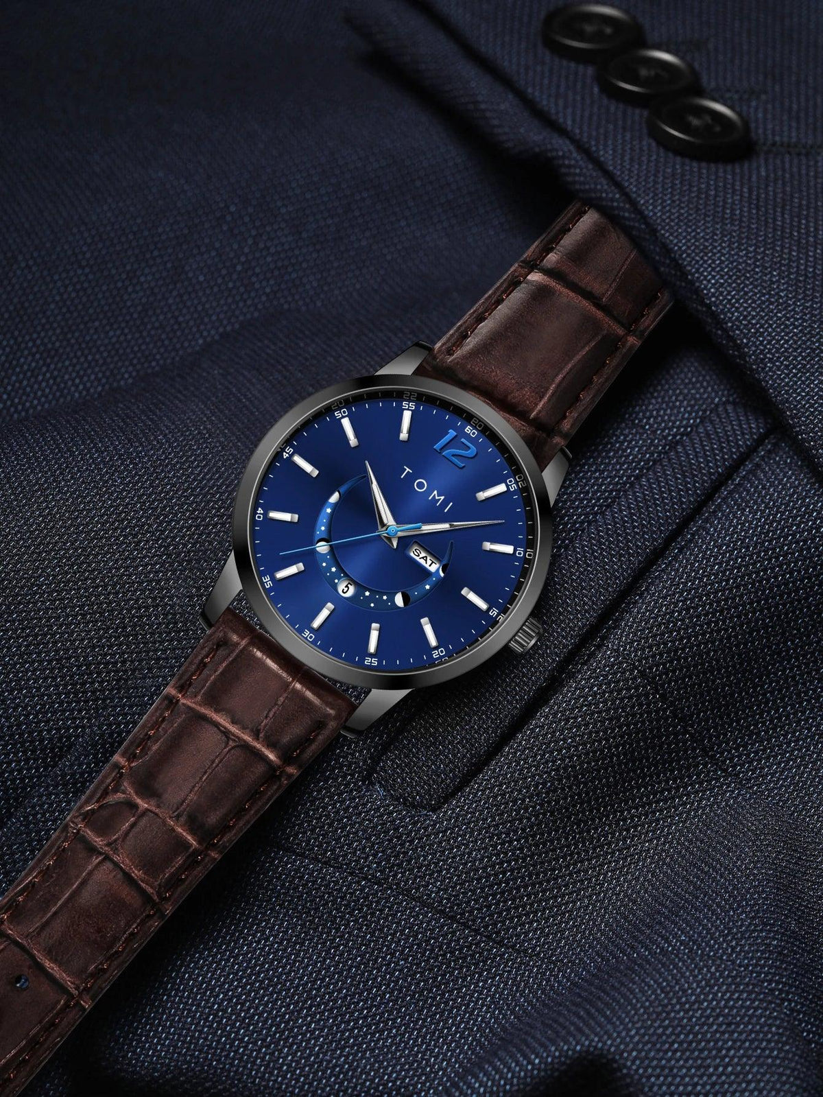 Watch with a blue face and brown leather strap on a dark suit background