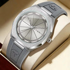 A silver-tone wristwatch with a brushed metal case, silver dial, and gray rubber strap, displayed inside a cream-colored presentation box. The strap features an embossed logo.