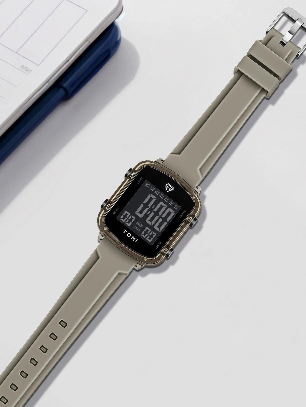 Digital watch with beige strap on a white surface