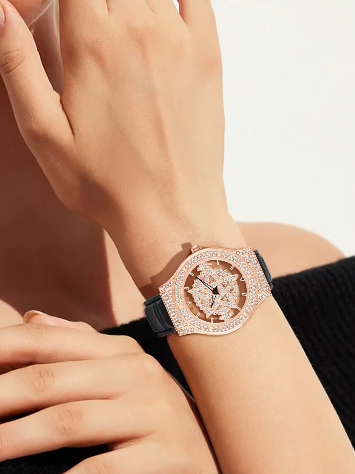 Luxury watch with rose gold case and black strap on a wrist against a neutral background